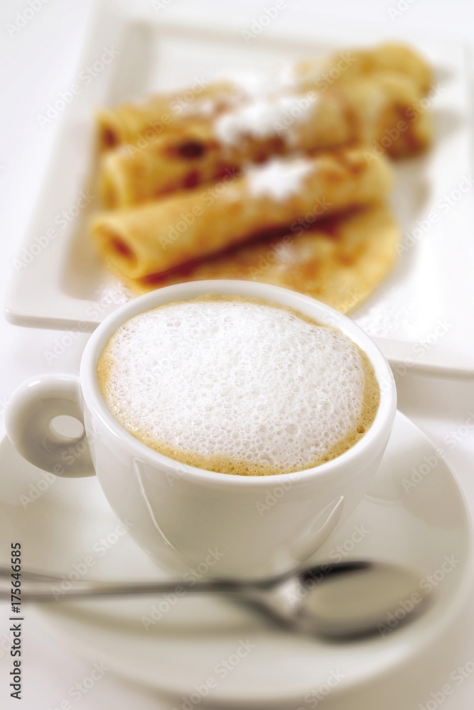 Cup of cappuccino, blurred crepes in background Cup of cappuccino, blurred crepes in background