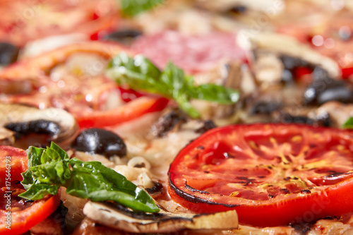 Closeup of pizza with salami, tomatoes and olives photo