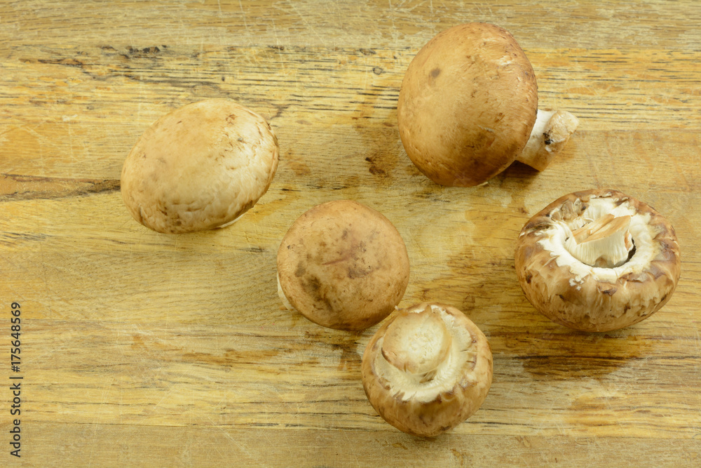 Close up of raw rinsed whole baby portabello mushrooms on rustic old cutting board Close up of raw rinsed whole baby portabello mushrooms on rustic old cutting board