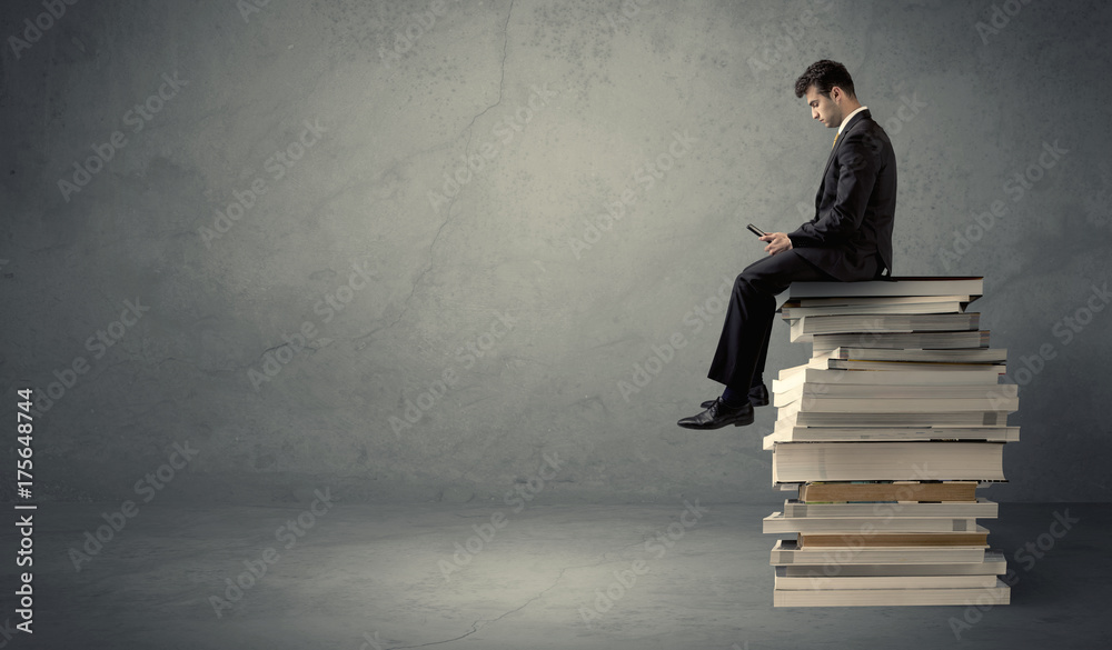 Student sitting on pile of books Student sitting on pile of books
