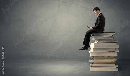 Student sitting on pile of books