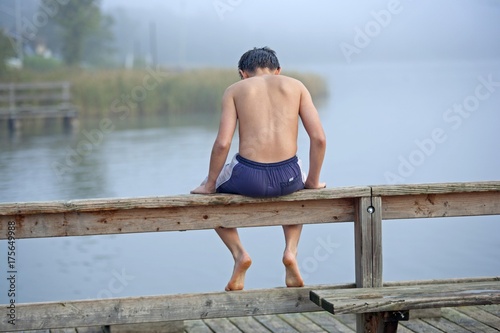 Boy sitting on a dock at a lake, Teterow, Mecklenburg-Western Pomerania, Germany, Europe