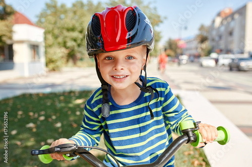 Boy in helmet standing with bike at autumn park