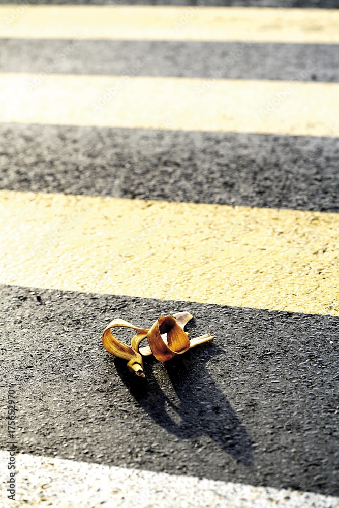 Obraz premium Banana peel on zebra crossing or crosswalk, symbol for accident risk