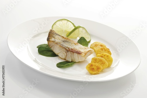 Seafood dish: zander filet, sliced limes, roasted potatoes and spinach leaves photo