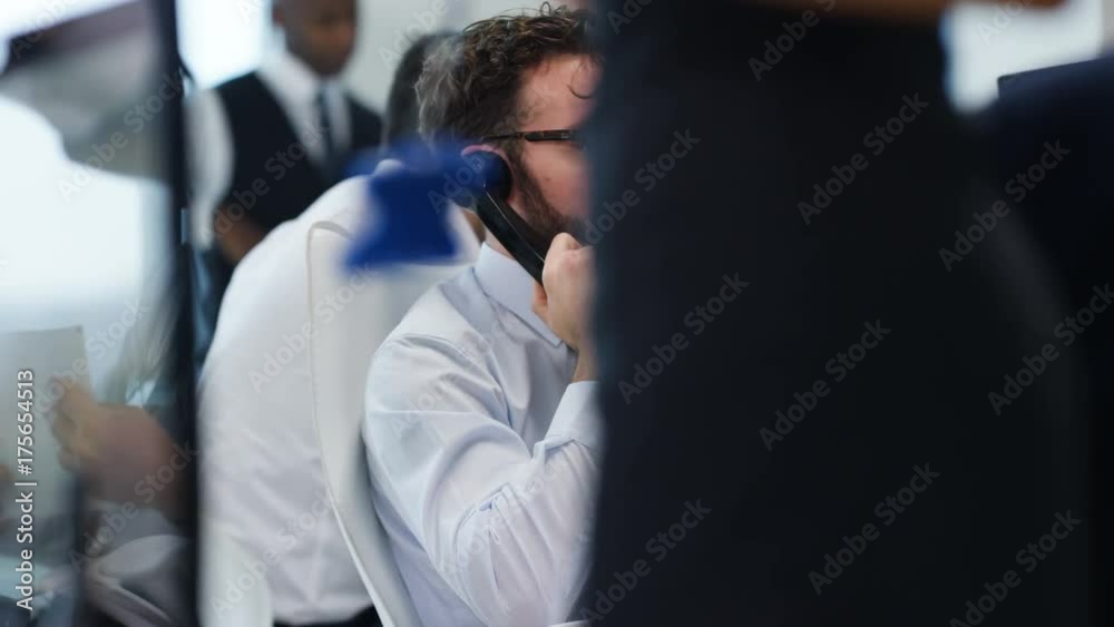Financial trader in busy stock exchange negotiating a deal over the phone Financial trader in busy stock exchange negotiating a deal over the phone