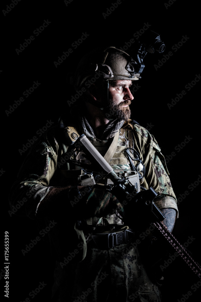 Studio contour backlight shot of special forces soldier in uniforms with weapons, portrait on black background