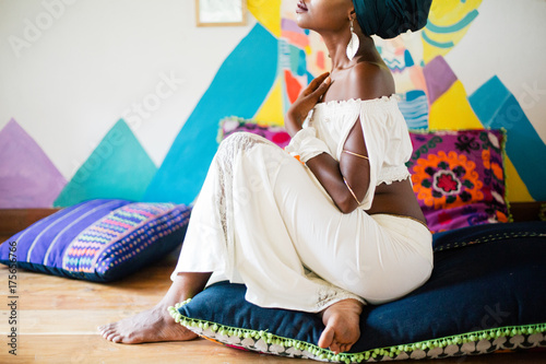 Young african woman sitting on the cushion floor in exotic colorful design space photo