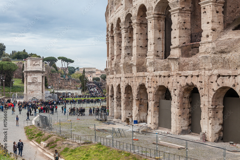 Fototapeta premium a view of Colosseum in Rome with trees on a sunny summer day and tourist