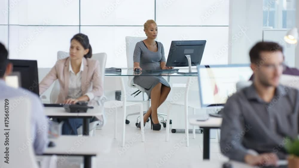 Pregnant businesswoman handing out paperwork to her colleagues in office Pregnant businesswoman handing out paperwork to her colleagues in office