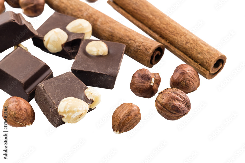 Pieces of bitter dark chocolate cubes with hazelnut and cinnamon stick isolated on white background