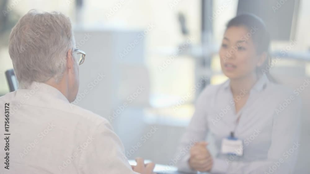 Audiology doctor showing patient a modern hi tech hearing aid & explaining Audiology doctor showing patient a modern hi tech hearing aid & explaining