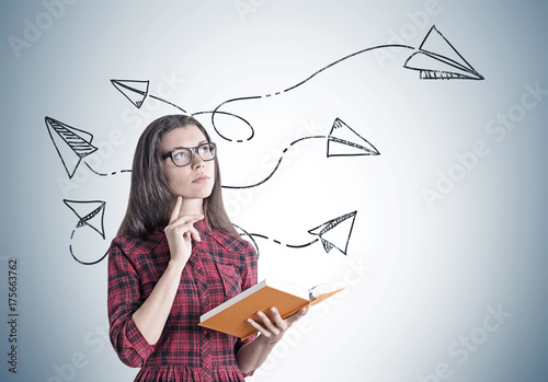 Young woman in a dress with a book, paper planes photo