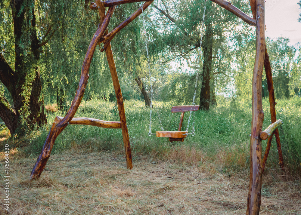 A wooden swing in the park. Eco-friendly materials in green environment A wooden swing in the park. Eco-friendly materials in green environment
