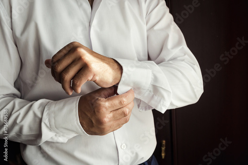 Businessman dress shirt. The man in the white shirt in the window dress cufflinks. Politician, man's style, Businessman buttoning his shirt,male hands closeup, American, European businessman
