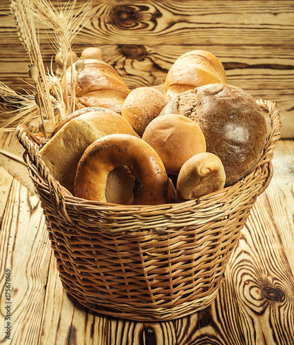 Bread in basket,Composition with variety of baking products on wooden table. Bread and buns inside basket. Fresh bakery products on table.Cereal products. Bakery and grocery concept