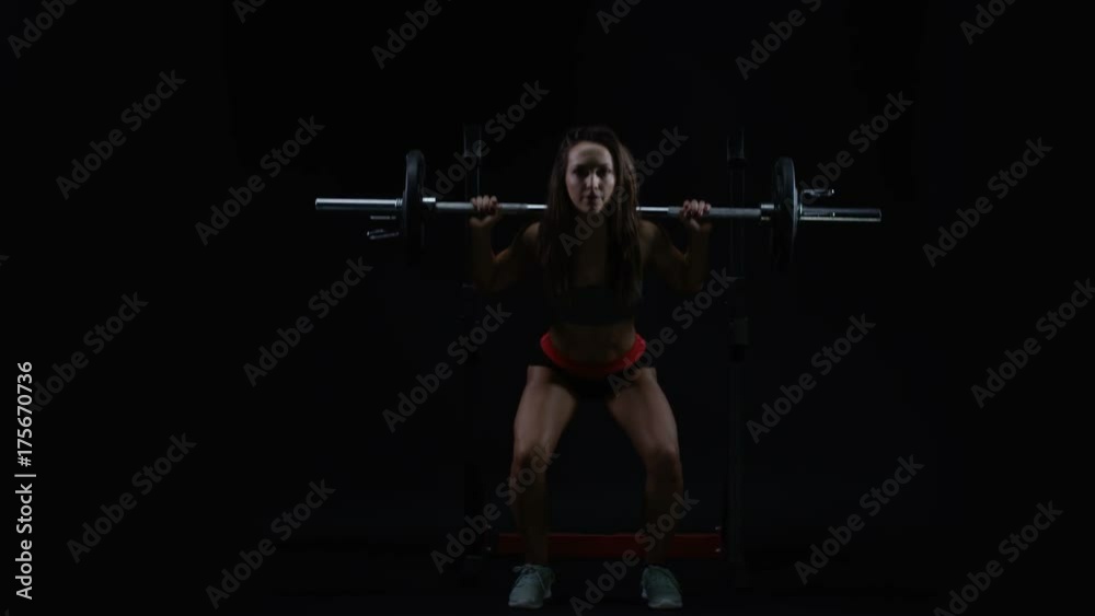 Fit young woman weight training, doing squats with barbell Fit young woman weight training, doing squats with barbell