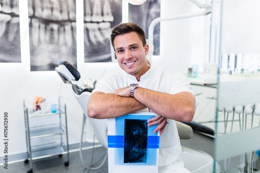 Portrait of handsome smiling dentist holding x-ray image of his patient. Portrait of handsome smiling dentist holding x-ray image of his patient.