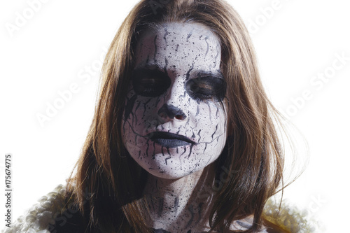 Brunette girl with a painted demon face. Creative make up in her face. Over a white background  isolated.