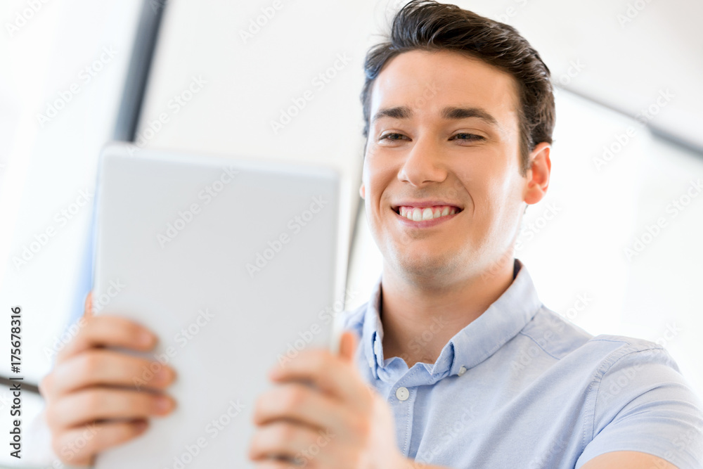 Young handsome businessman using his touchpad sitting in office