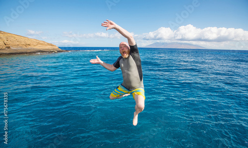 Bald man jumping into the ocean
