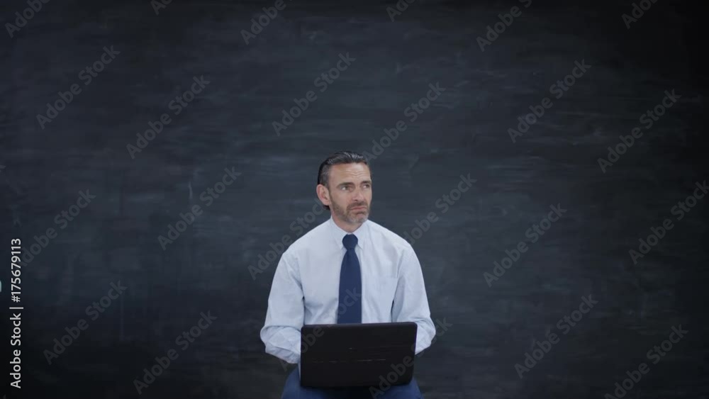 Man with laptop looking for inspiration on blank chalkboard background Man with laptop looking for inspiration on blank chalkboard background