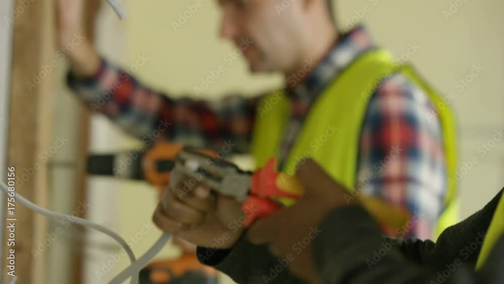  Construction workers on a building site drilling & checking wiring