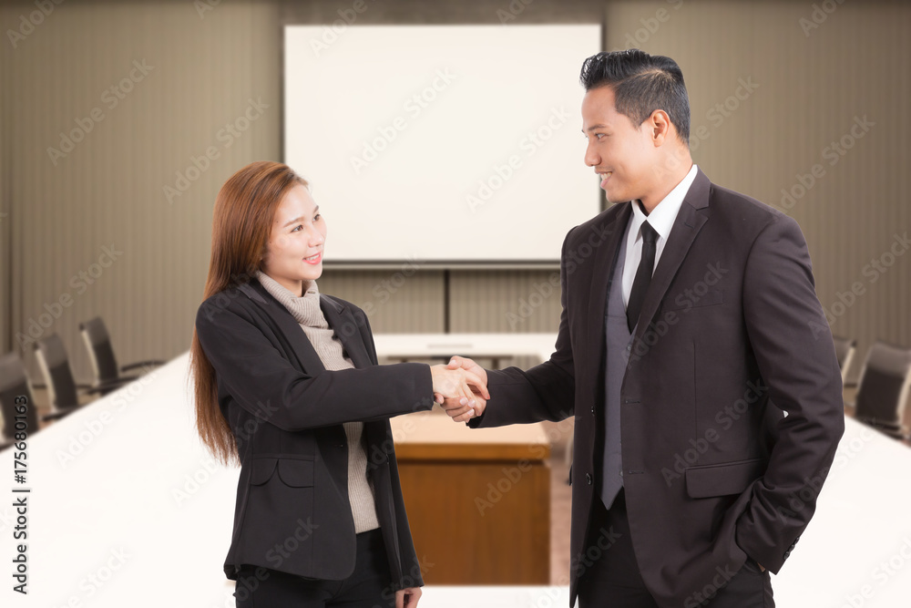 Businessman and woman shaking hands in conference room background. Businessman and woman shaking hands in conference room background.