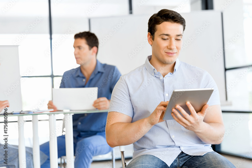 Young handsome businessman using his touchpad sitting in office Young handsome businessman using his touchpad sitting in office