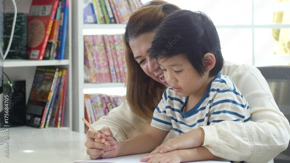 Asian mother helping her son doing homework on white table Asian mother helping her son doing homework on white table