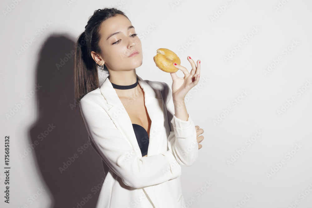 Brunette girl with a classic glase donut. Over a white background. Brunette girl with a classic glase donut. Over a white background.