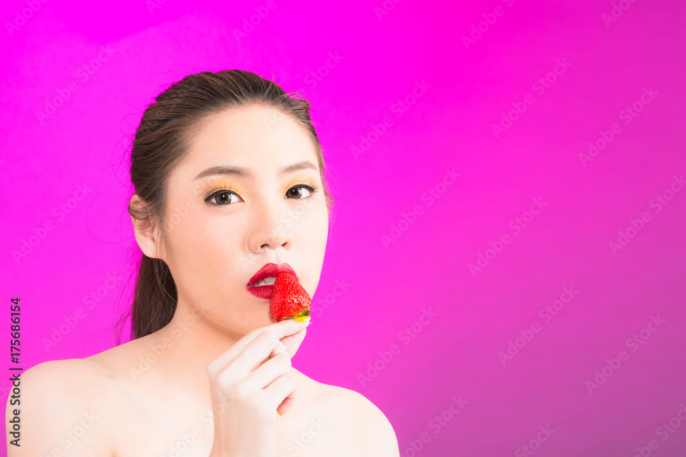 Young Asian woman kissing strawberry isolated in pink background. Young Asian woman kissing strawberry isolated in pink background.
