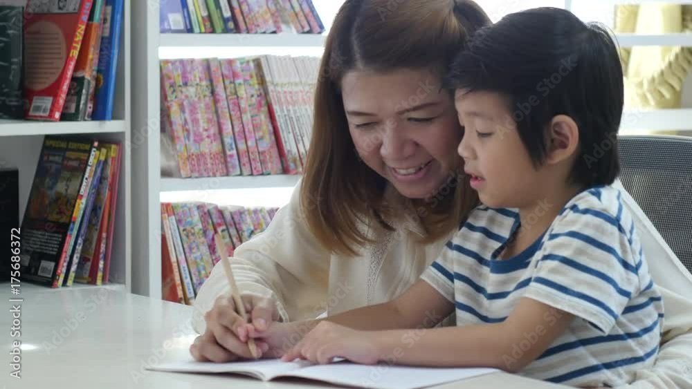 Asian mother helping her son doing homework on white table Asian mother helping her son doing homework on white table