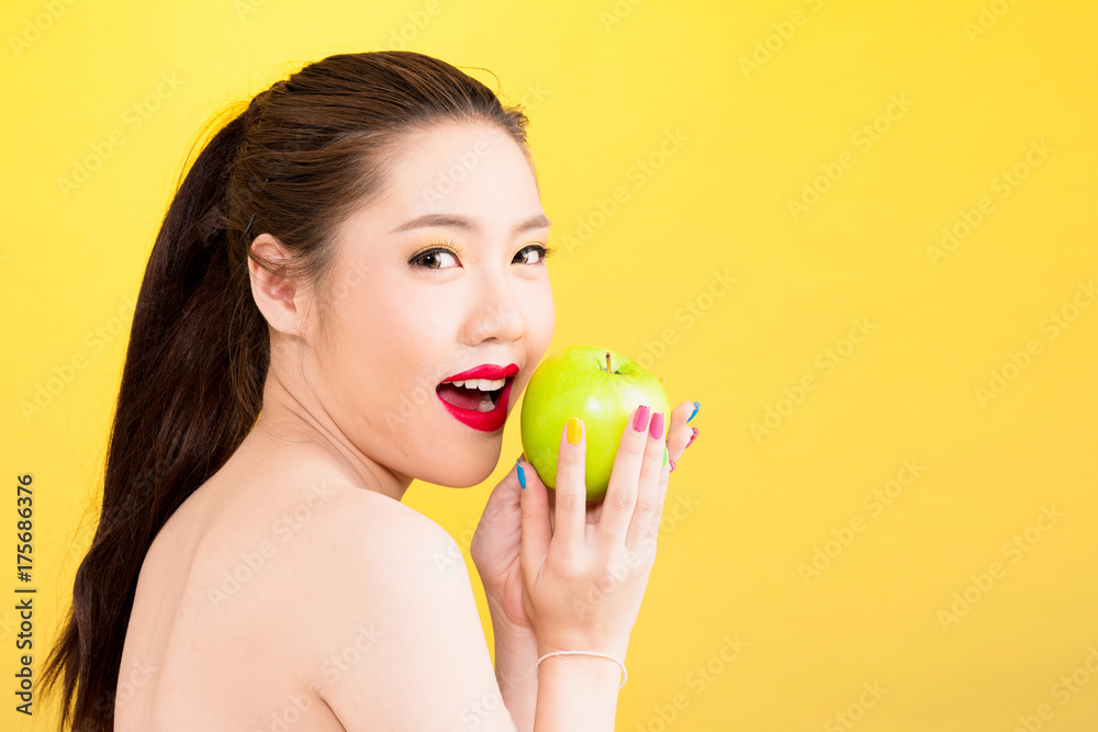 Young Asian woman holding apple isolated in yellow background Young Asian woman holding apple isolated in yellow background
