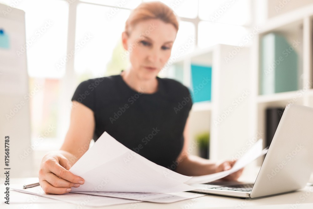 Fototapeta premium Busy economist with papers learning information for new project