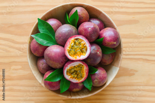 Fresh passion fruit in wood bowl on wood table in top view flat lay with copy space for background or wallpaper. Ripe passion fruit so delicious sweet and sour. Passion fruit is tropical fruit.