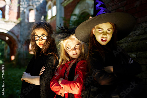 Frightening girls leaning against wall of building on halloween evening outdoors