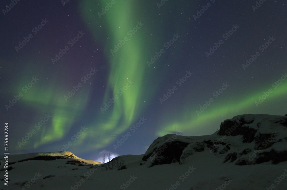 Naklejka premium The snow covered the hills and in the sky the stars and the aurora borealis.