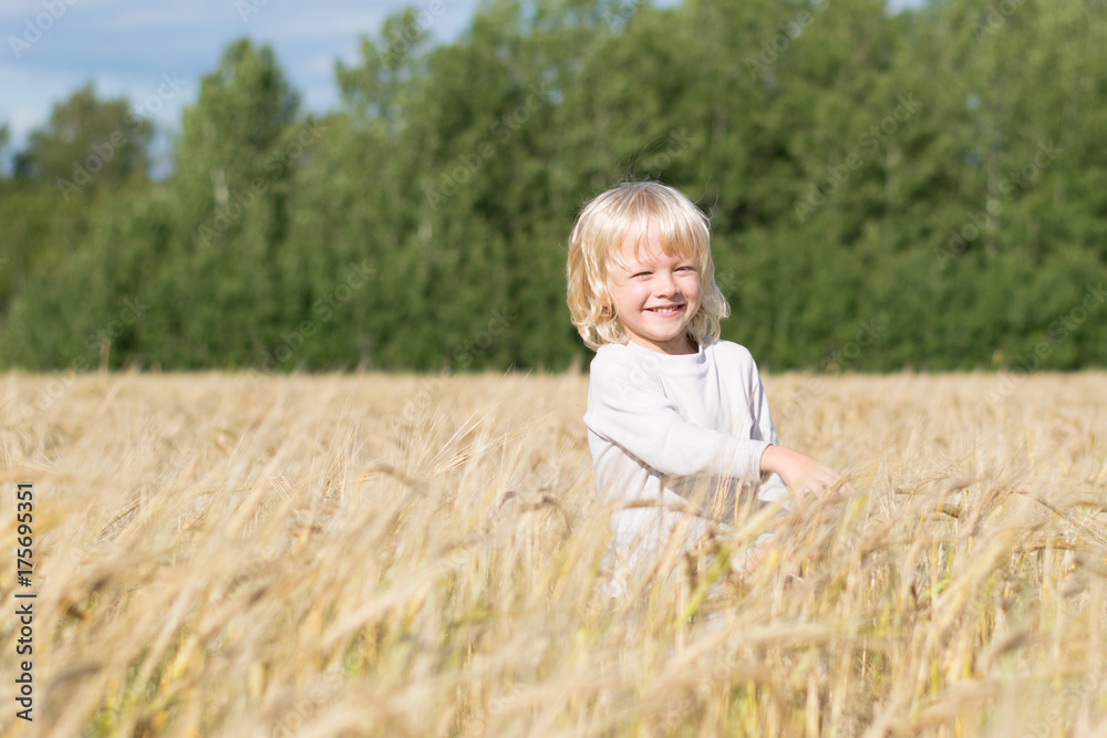 Blond Slavic happy kid boy at a ripe rye wheat field, autumn harvest, Russian forest, the Urals