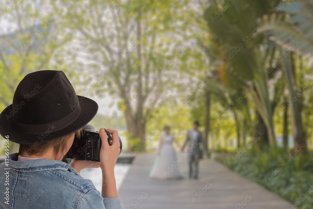 Portrait  of wedding photographer in action,  attractive young woman shooting pictures wedding at park. This image for behind the scenes concept.