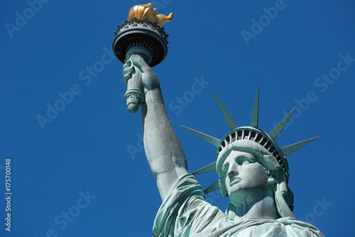 Statue of Liberty with golden torch in a sunny day, blue sky in New York © andersphoto