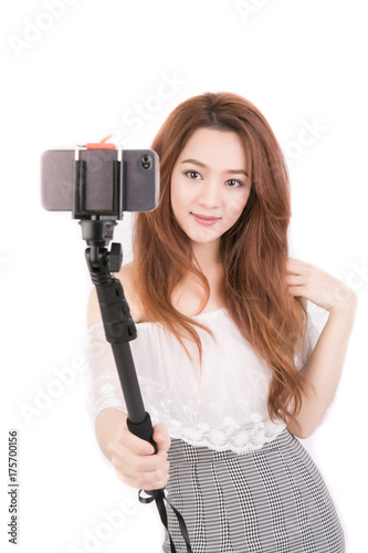 Portrait of beautiful young asian woman making selfie and standing against on white background. Thai girl use monopod selfie.