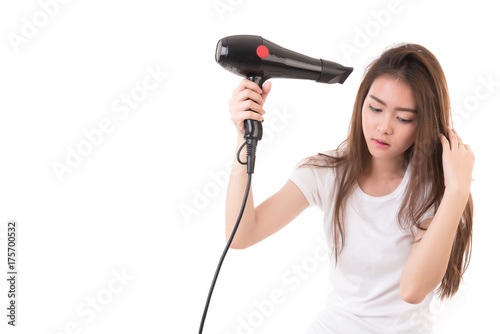 Asian woman uses hair dryer on white background.