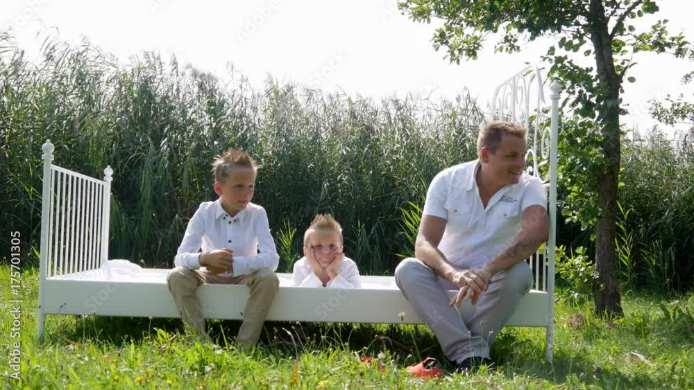 Family in white clothes, with three children in the nature with a white bed