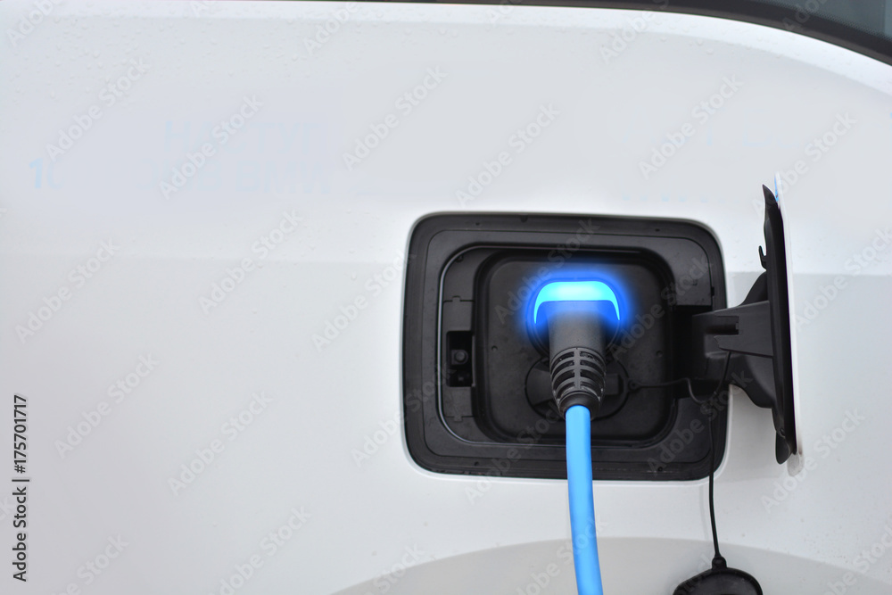 Charging an electric vehicle. Blue charging indicator light. Fuel of the future. Charging an electric vehicle. Blue charging indicator light. Fuel of the future.