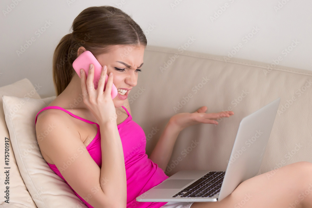 Angry mad young woman arguing on cellphone about broken laptop problem sitting on sofa at home, furious disgruntled customer calling service support complaining on bad internet or computer failure Angry mad young woman arguing on cellphone about broken laptop problem sitting on sofa at home, furious disgruntled customer calling service support complaining on bad internet or computer failure