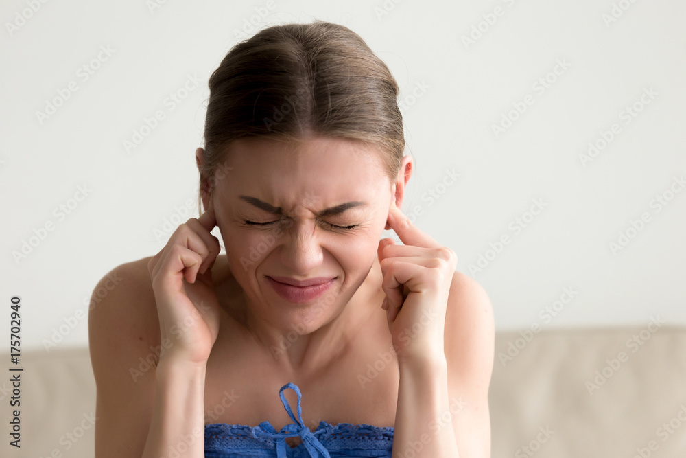 Young annoyed woman sticking fingers in ears with eyes closed, not listening to loud noise, ignoring stressful environment, stubborn teen refuses hearing, feels ear ache, tinnitus, head shot portrait Young annoyed woman sticking fingers in ears with eyes closed, not listening to loud noise, ignoring stressful environment, stubborn teen refuses hearing, feels ear ache, tinnitus, head shot portrait