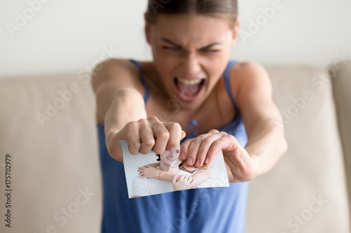 Angry hysterical woman tearing photo of happy couple, erasing memories of ex-boyfriend after breaking up divorce, frustrated lovelorn teenager feeling heartbroken ripping picture of past relationship photo