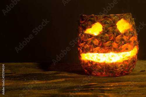 Pineapple Halloween jack lantern placed on the wooden floor and old wooden backdrop.