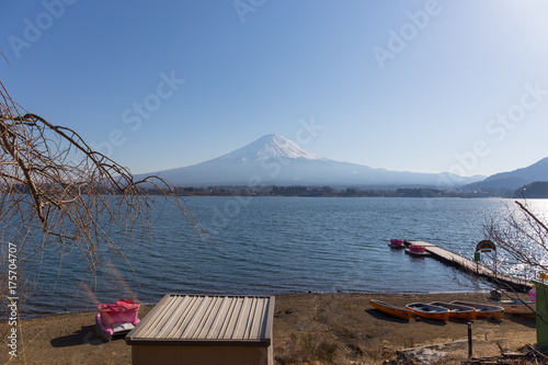 Fuji mountain and small dock on kawaguchiko lake with branches foreground photo